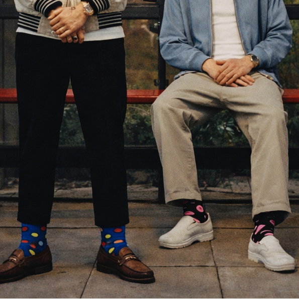 Two men standing and sitting on a bench with a scenic background